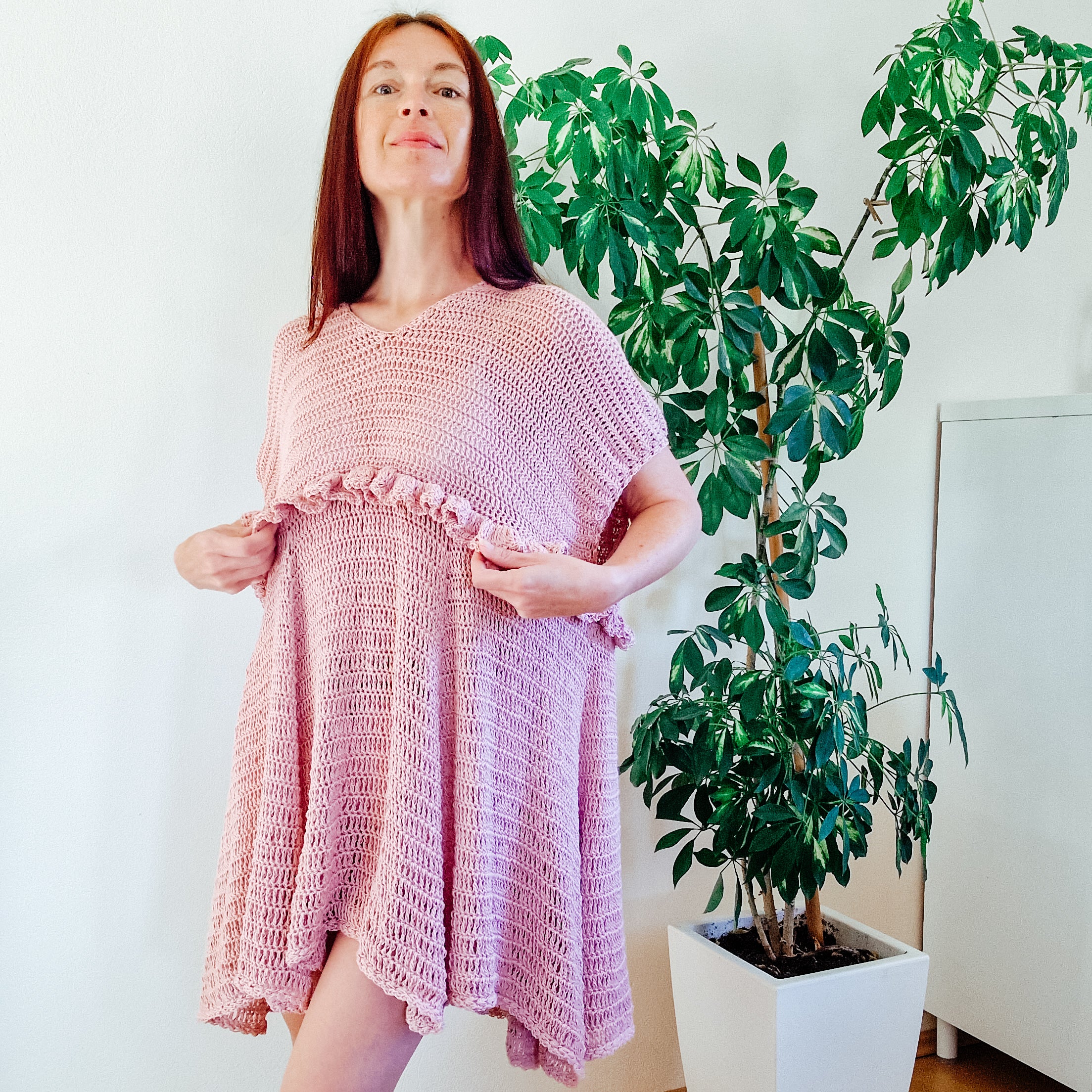 Loops Only blush ruffle summer dress hanging on a wooden hanger, lightweight fabric with floral pattern and ruffled neckline.